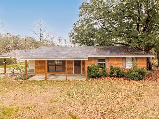 ranch-style house with a front yard, a patio, and brick siding