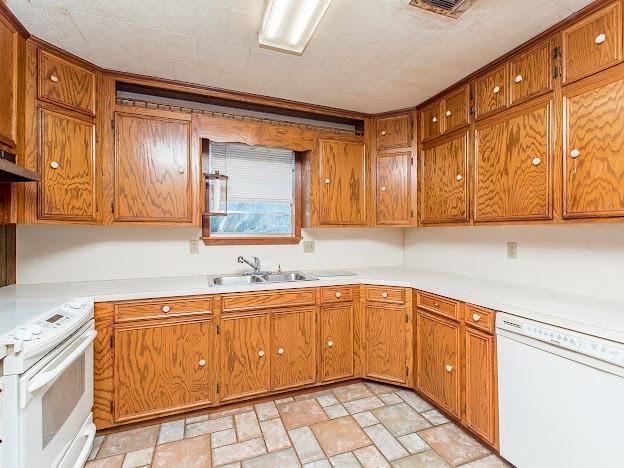 kitchen featuring light countertops, white appliances, and brown cabinetry