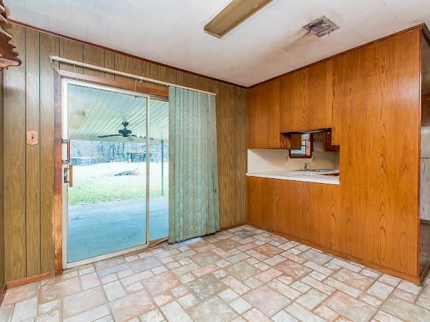 kitchen with light countertops, wooden walls, and brown cabinets