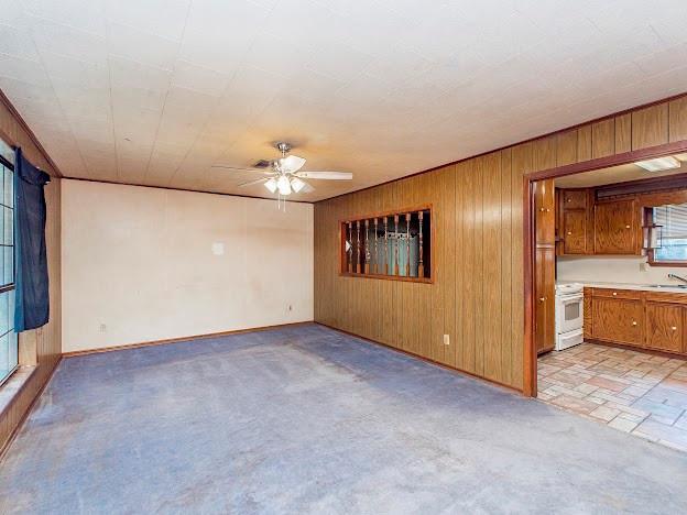 unfurnished living room with wood walls, a sink, and a ceiling fan