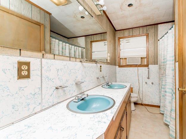 full bathroom with toilet, double vanity, a sink, and tile patterned floors