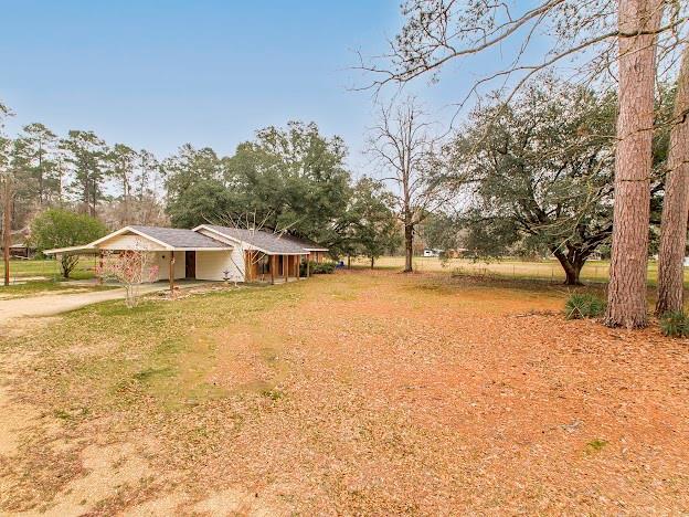 view of yard with dirt driveway and an attached carport