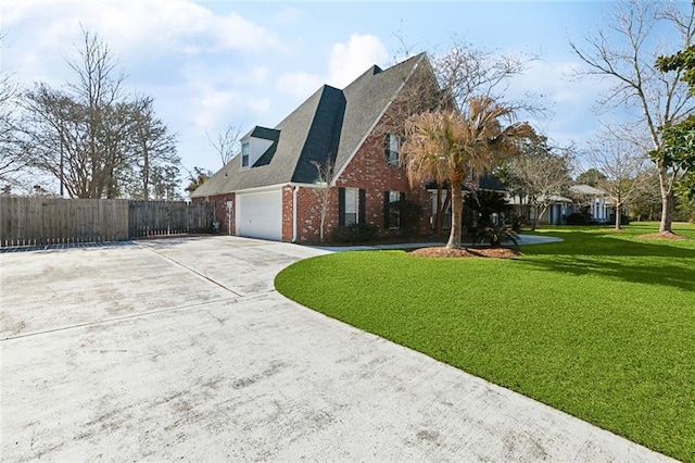 view of home's exterior with an attached garage, brick siding, fence, a yard, and driveway