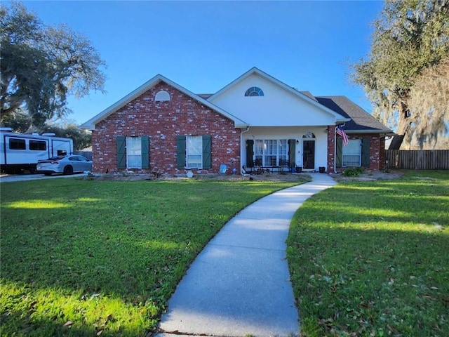 view of front of house with brick siding, a front yard, and fence