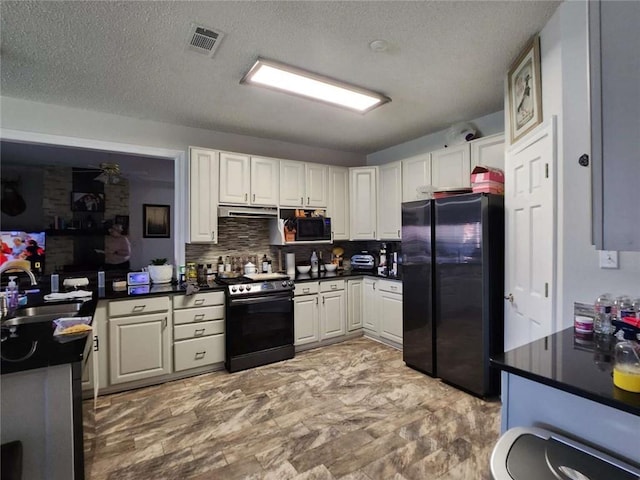 kitchen with dark countertops, black appliances, white cabinets, and a sink