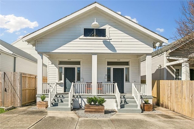 shotgun-style home featuring a porch and fence