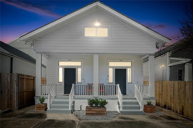 shotgun-style home featuring a porch and fence