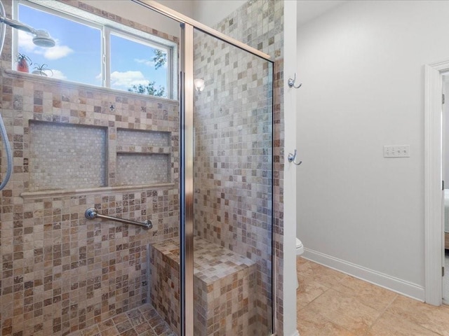 bathroom featuring toilet, a stall shower, and baseboards