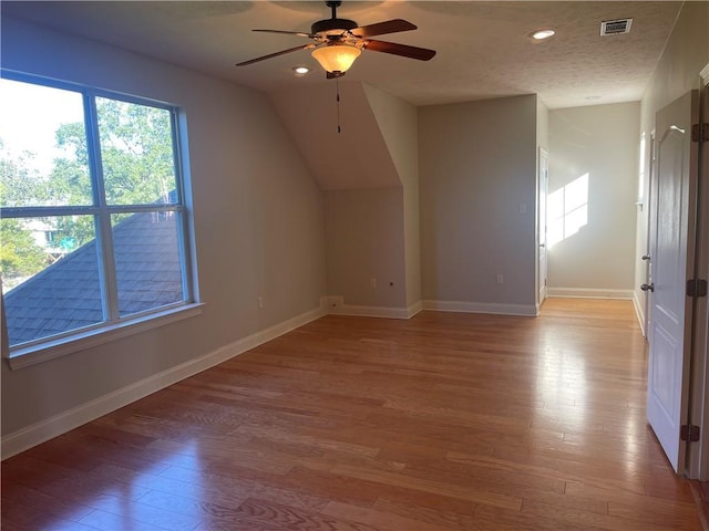 additional living space with light wood finished floors, visible vents, baseboards, a textured ceiling, and recessed lighting