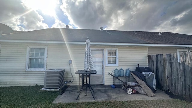 back of house featuring a patio area, fence, central AC unit, and roof with shingles