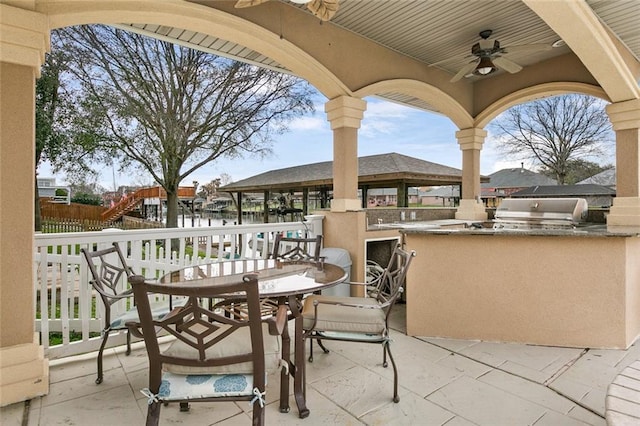 view of patio with area for grilling, fence, a ceiling fan, a water view, and grilling area