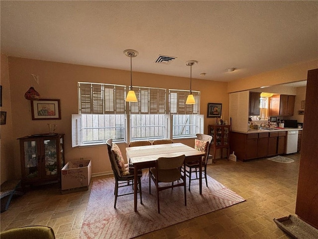 dining area with visible vents, a textured ceiling, and baseboards