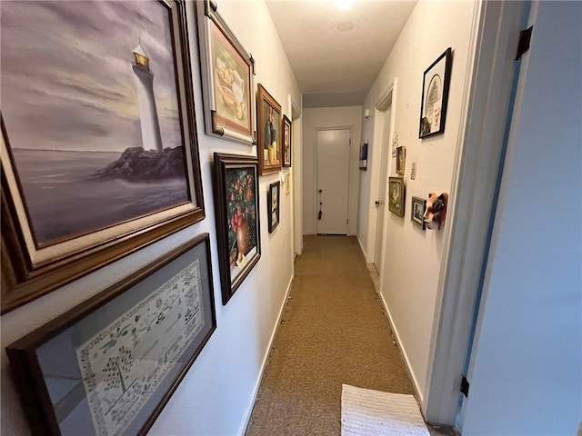 hallway featuring dark carpet and baseboards