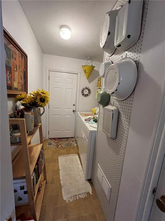 washroom featuring visible vents, stone finish floor, a textured ceiling, separate washer and dryer, and laundry area