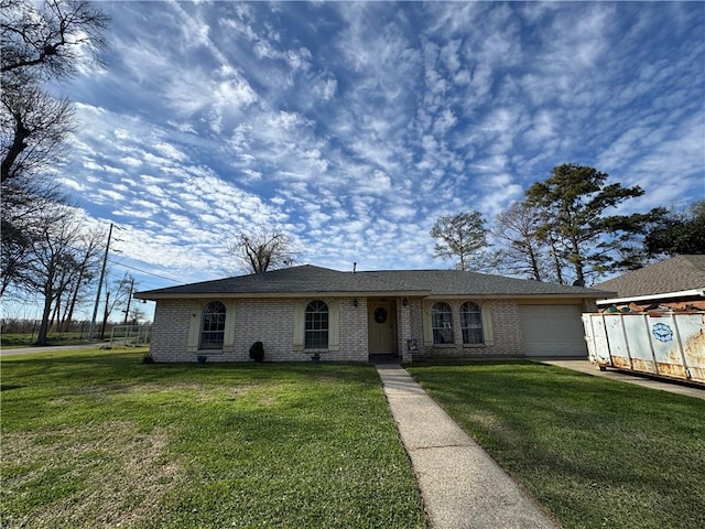 ranch-style home with an attached garage, brick siding, fence, driveway, and a front yard