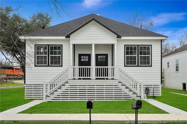 bungalow featuring roof with shingles, a front lawn, and stairs