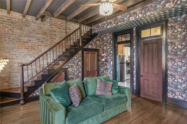 unfurnished living room featuring stairway, wood finished floors, beam ceiling, and wallpapered walls