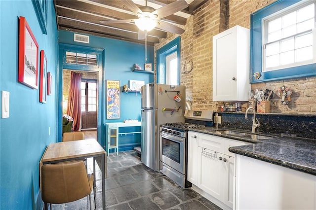 kitchen featuring a sink, visible vents, white cabinets, appliances with stainless steel finishes, and dark stone counters