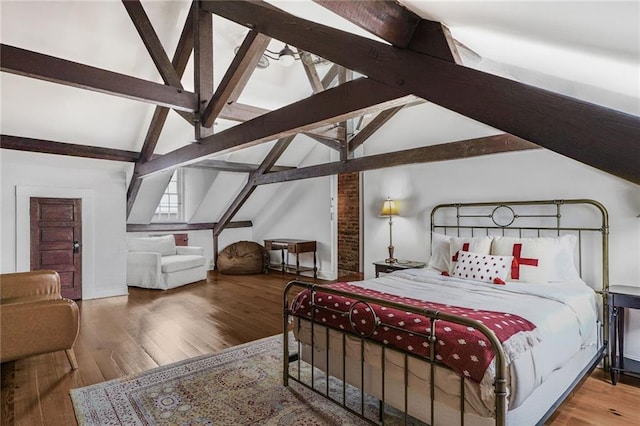 bedroom with lofted ceiling with beams and wood finished floors