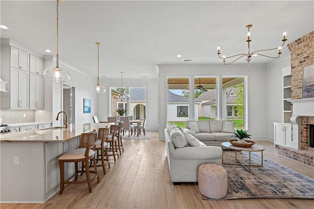 4221 Cypress Point Dr, Covington, LA 70433 - living room with an inviting chandelier, light wood-style floors, plenty of natural light, and a fireplace