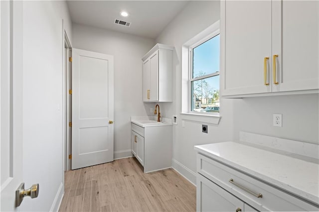 4221 Cypress Point Dr, Covington, LA 70433 - clothes washing area with visible vents, baseboards, light wood-style floors, electric dryer hookup, and cabinet space