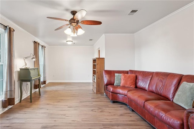 living room featuring light wood-style floors, visible vents, a ceiling fan, and ornamental molding