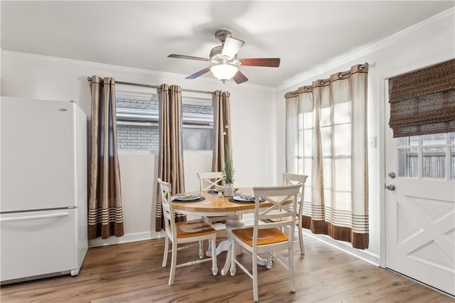 dining room with light wood-style floors, a ceiling fan, and crown molding