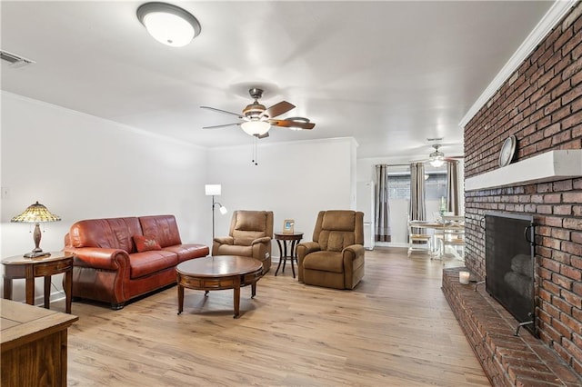 living room featuring ornamental molding, visible vents, light wood finished floors, and a ceiling fan