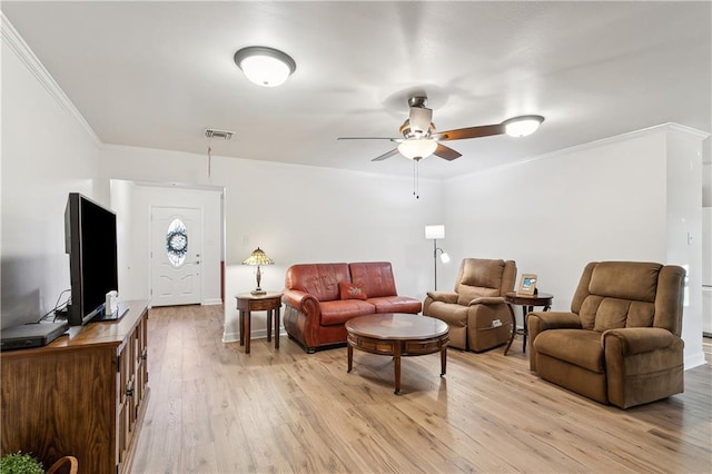 living area featuring baseboards, visible vents, a ceiling fan, light wood-style flooring, and ornamental molding