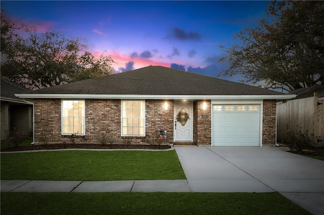 single story home with a garage, concrete driveway, brick siding, and a yard