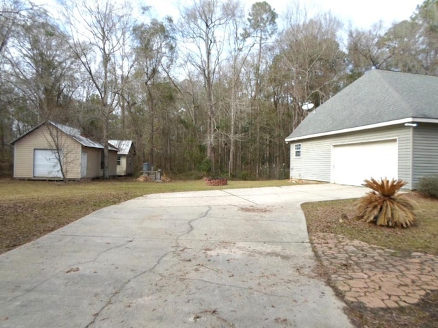 view of property exterior featuring driveway, a shingled roof, and an outbuilding