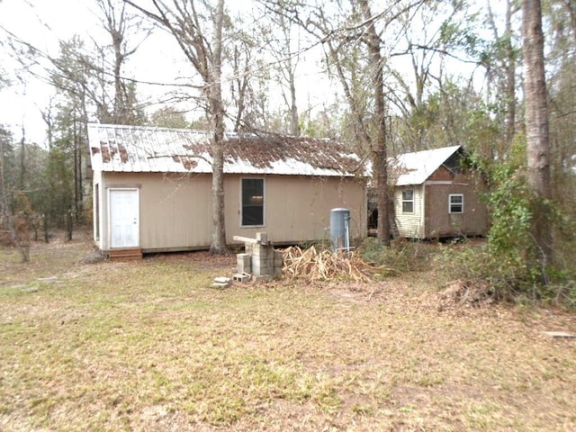 back of house featuring metal roof and a lawn