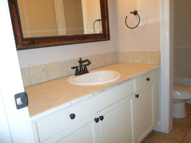 bathroom featuring toilet, tile patterned flooring, backsplash, and vanity