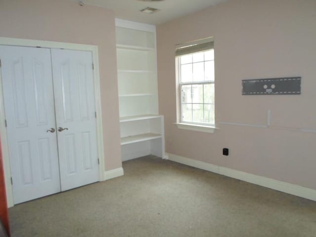 unfurnished bedroom featuring a closet, light colored carpet, and baseboards