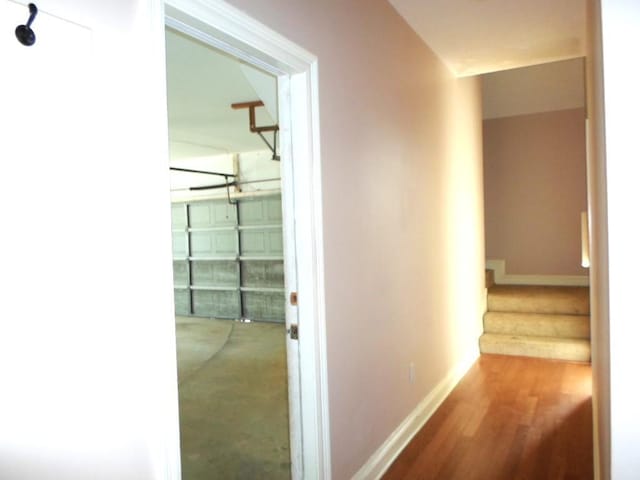 corridor featuring stairway, wood finished floors, and baseboards