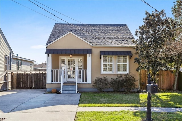 bungalow-style house featuring a shingled roof, a front lawn, fence, and stucco siding