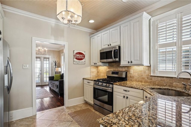 kitchen with appliances with stainless steel finishes, pendant lighting, white cabinetry, and a sink