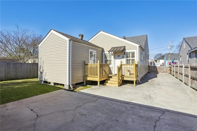 view of front facade featuring a shingled roof, a front yard, a patio area, and a fenced backyard