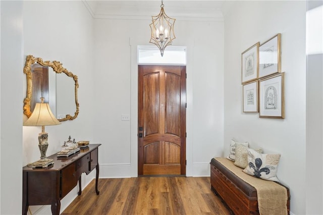 foyer featuring ornamental molding, dark wood-type flooring, baseboards, and an inviting chandelier