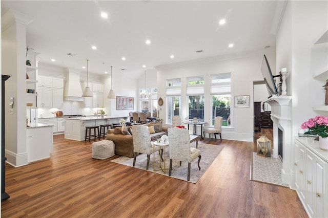 dining space featuring crown molding, recessed lighting, a fireplace with flush hearth, wood finished floors, and baseboards