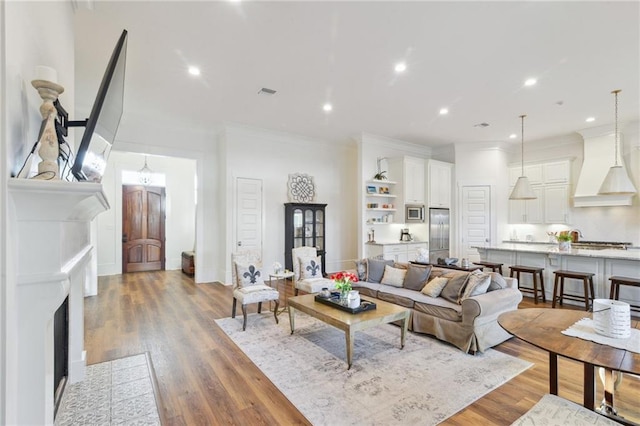 living area featuring recessed lighting, wood finished floors, and crown molding