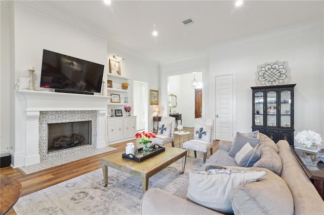 living room featuring a fireplace, baseboards, crown molding, and wood finished floors