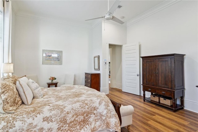 bedroom featuring ceiling fan, baseboards, crown molding, and wood finished floors