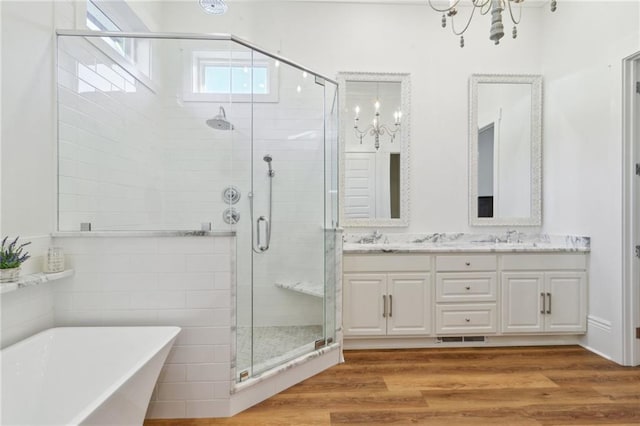 bathroom featuring double vanity, wood finished floors, a soaking tub, and a shower stall