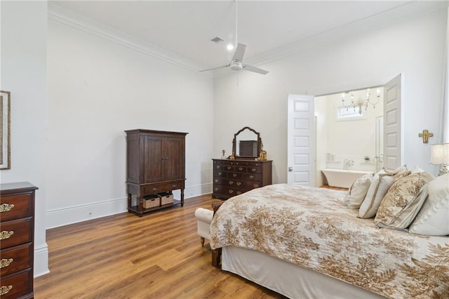 bedroom with crown molding, a ceiling fan, ensuite bath, wood finished floors, and baseboards