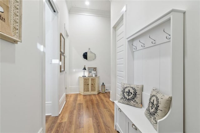 mudroom featuring ornamental molding, baseboards, and wood finished floors