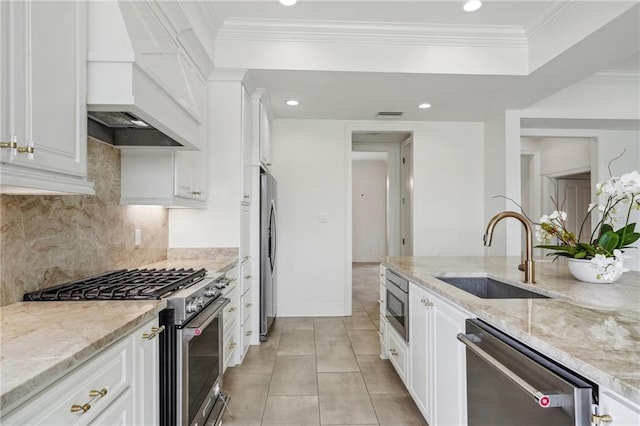 kitchen with custom range hood, light stone counters, stainless steel appliances, and a sink