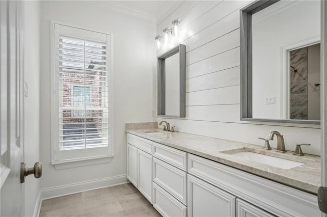 bathroom with double vanity, crown molding, baseboards, and a sink