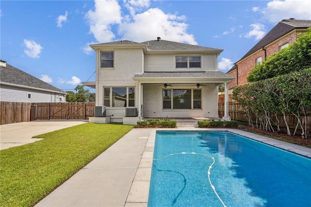 back of house featuring a ceiling fan, a fenced in pool, a fenced backyard, and a lawn