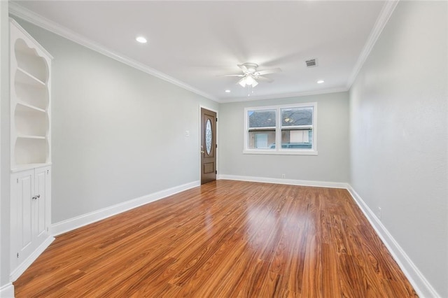 spare room featuring ceiling fan, ornamental molding, wood finished floors, and baseboards